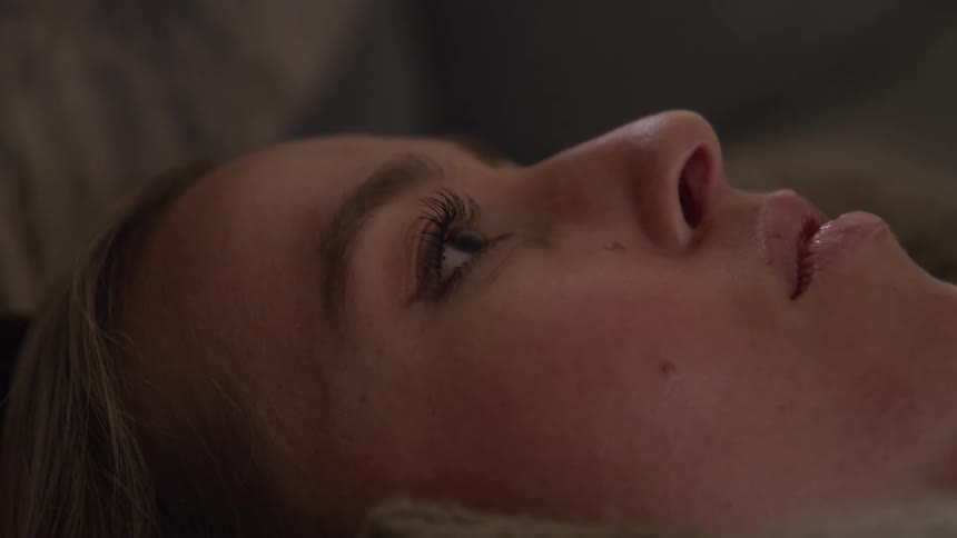 A woman lying down looking up thoughtfully