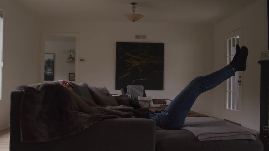 A woman falls back onto her sofa