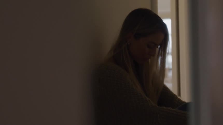 A woman sitting on the floor with her head down crying