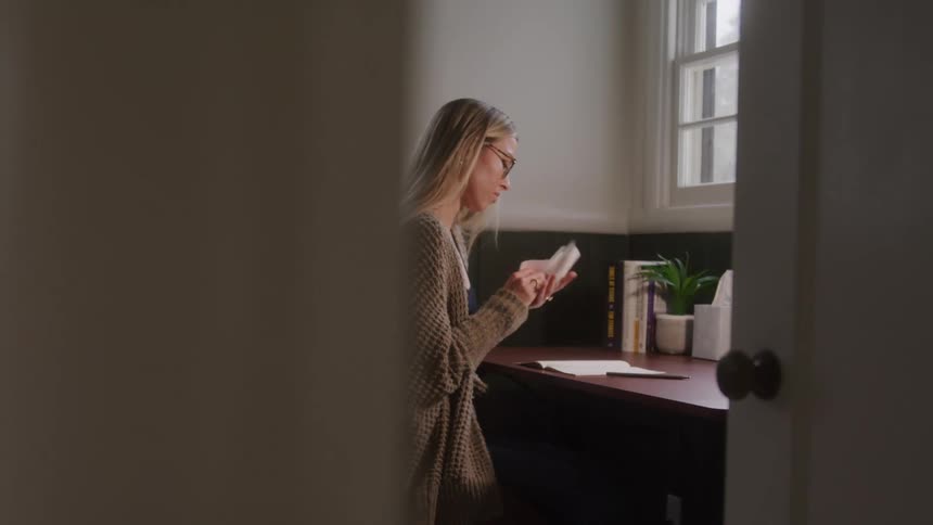 Woman sitting at a desk throwing away a piece of paper