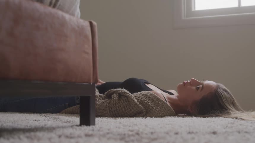 A young woman lies on a rug indoors