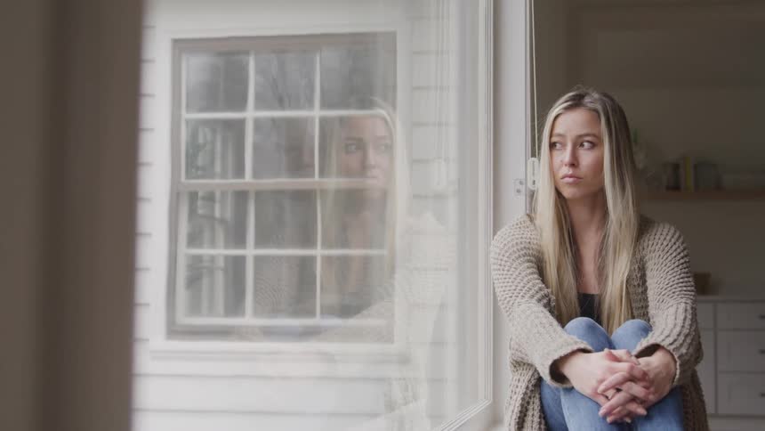 A woman sadly looks out the window