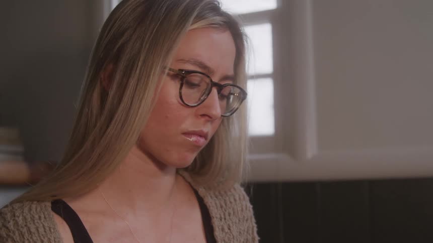Blonde woman crumples up a piece of paper before continuing to concentrate on her task