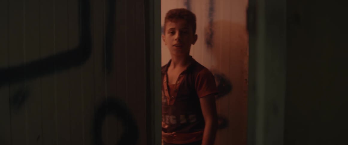 A boy is looking through a dark hall