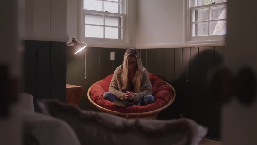 Woman sitting with her head down in an armchair in a room