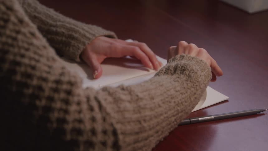 The woman writing stops to tear out a page from her notebook
