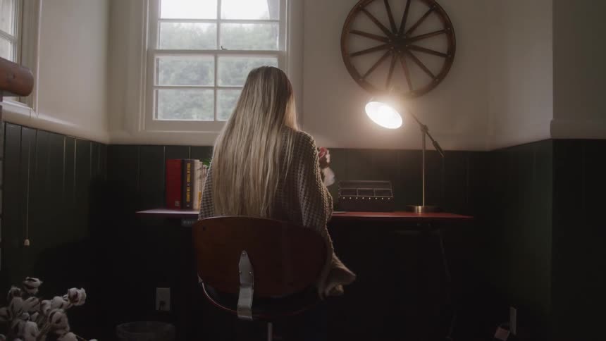 A woman sitting down tears a paper on the table crumples it and throws it behind her