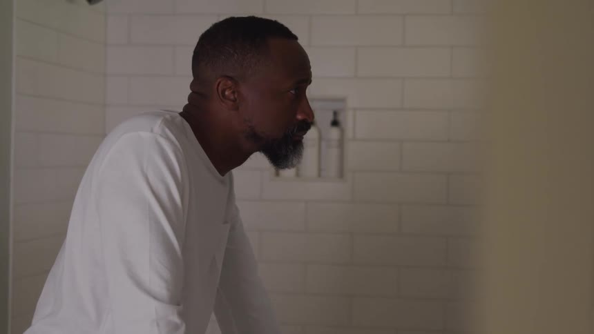 The man looks up into the bathroom mirror