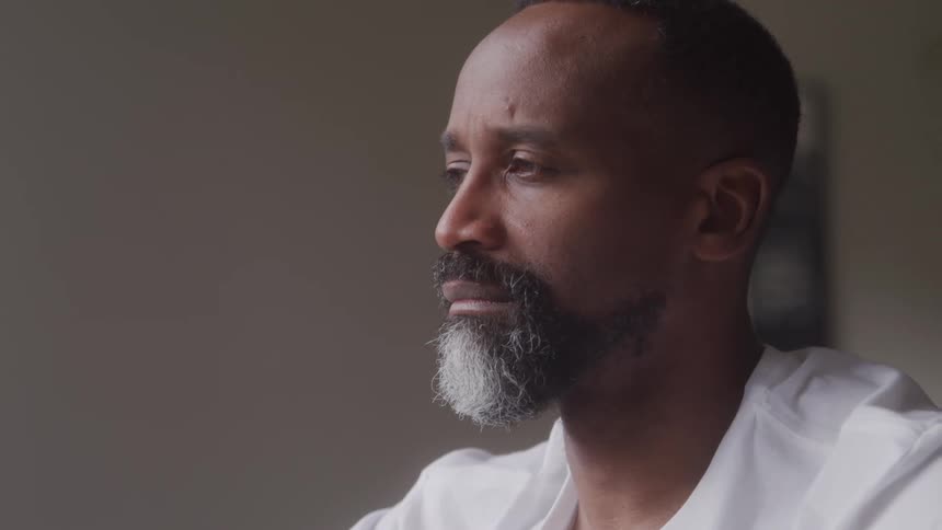 Man with a salt and pepper goatee blinks sadly