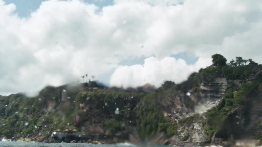 Ocean waves crash against a rocky shore causing heavy splashes at midday
