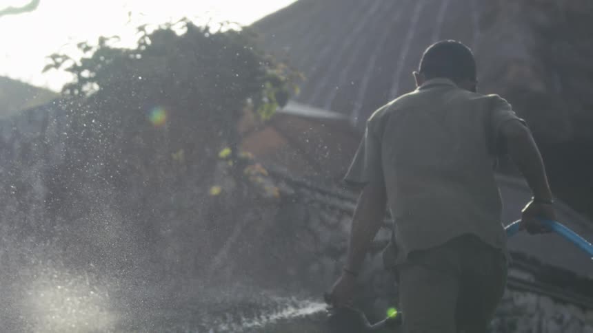 The gardener is watering the grass