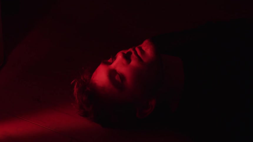 Man waking up while lying on the floor with a red light in his face