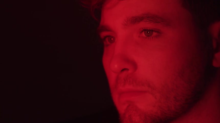 Portrait of a man with a red light on his face in a dark room