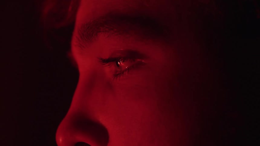Mans face lit by red light with eyes closed