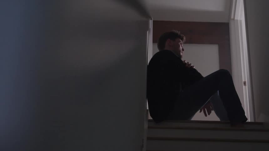 Man sitting on a staircase looking thoughtful