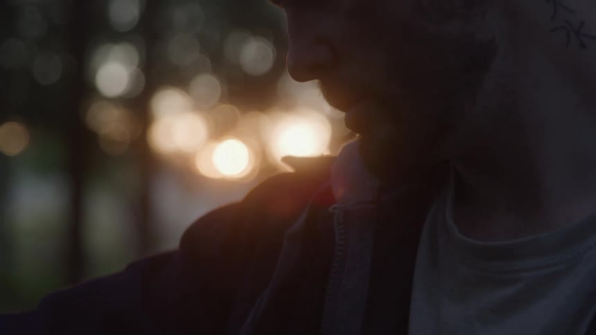 Side silhouette of a man is seen among trees with the sun in the background