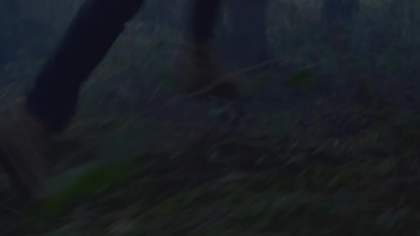 A man runs very fast through the woods at sunset