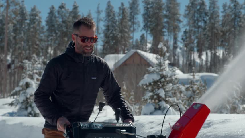 Closeup of a man operating a snowblower on a snowy path