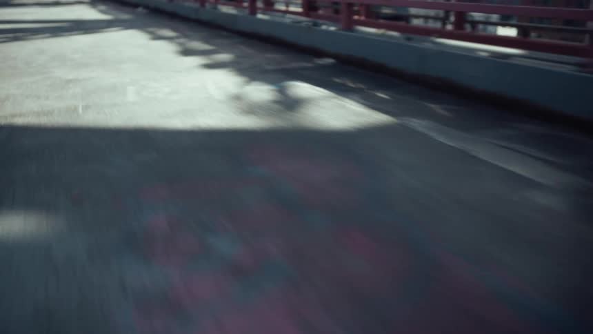 A lowangle view of a bridges pathway conveying a sense of rapid forward motion through light and shadow