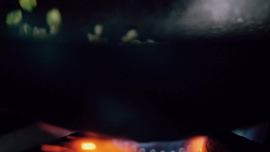 The video features a closeup of vegetables including green beans and chopped carrots along with what appears to be rice being stirfried in a dark pan the flames from the burner are visible beneath the pan indicating active cooking