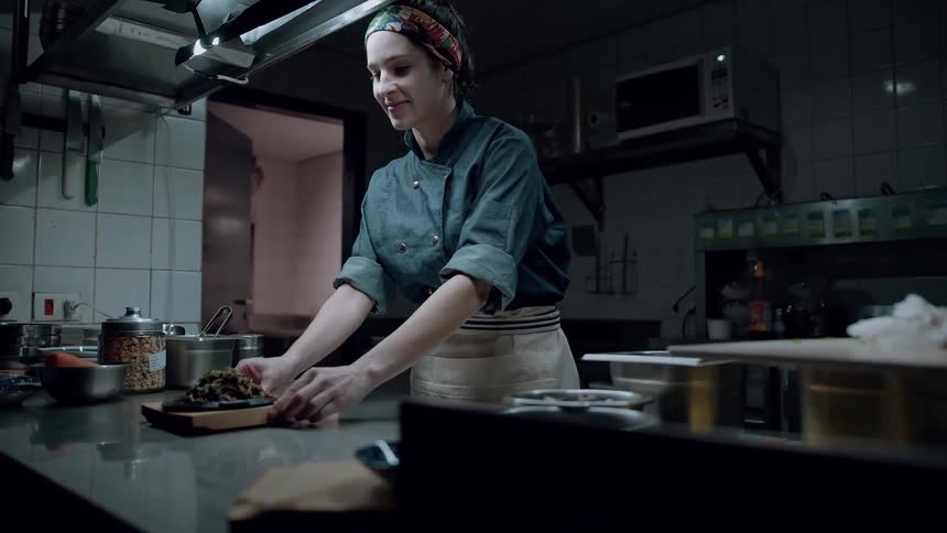 A chef presents a finished dish in a professional kitchen