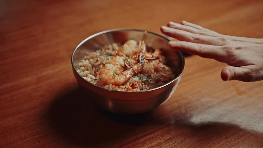 The woman finishes preparing a bowl of food