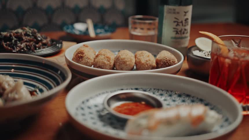 A table is set with a vibrant assortment of dumplings dipping sauces and fried appetizers
