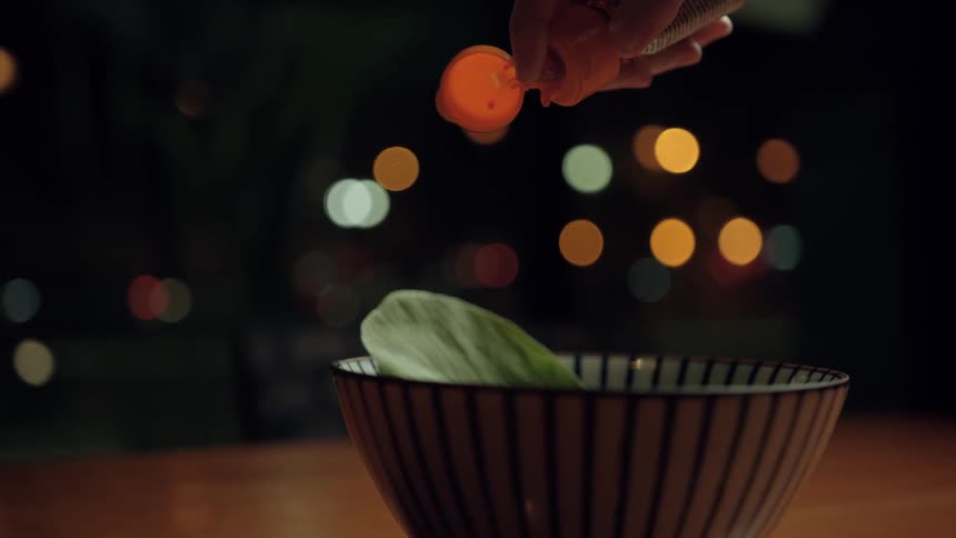 A person adds sauce to a bowl of food on a table