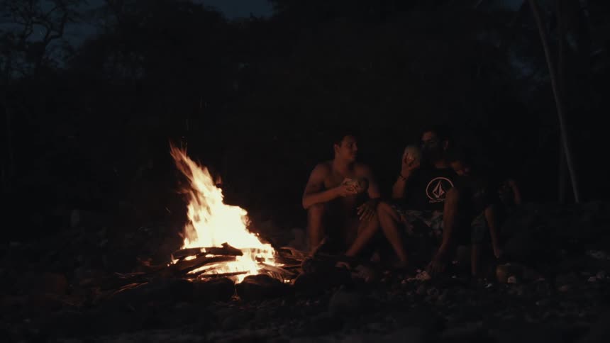 People sitting and enjoying by a campfire in the forest at night