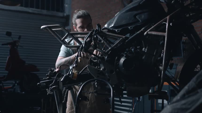 A mechanic works on a motorcycle inside a mechanic workshop