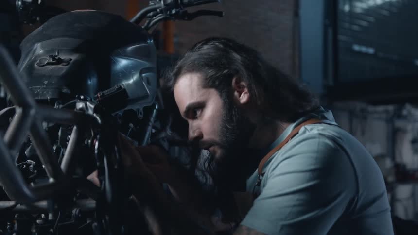 A man fixes a motorcycle inside a mechanic workshop