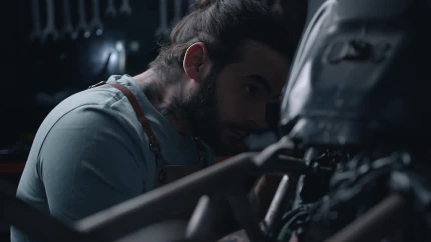 A mechanic works on a motorcycle inside a mechanic workshop
