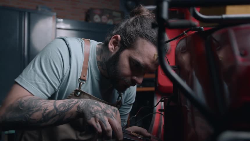 A mechanic repairs a red motorcycle in a repair shop