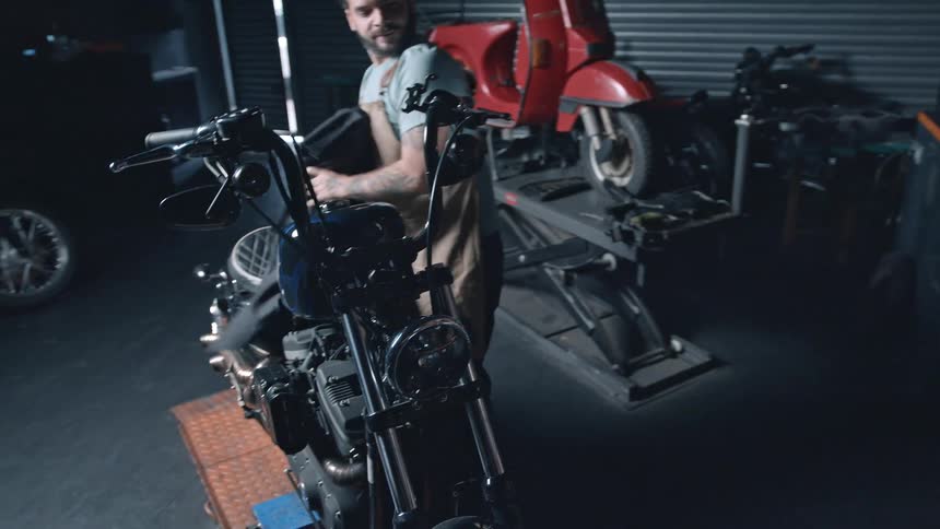 Man unveiling a motorcycle in a garage workshop