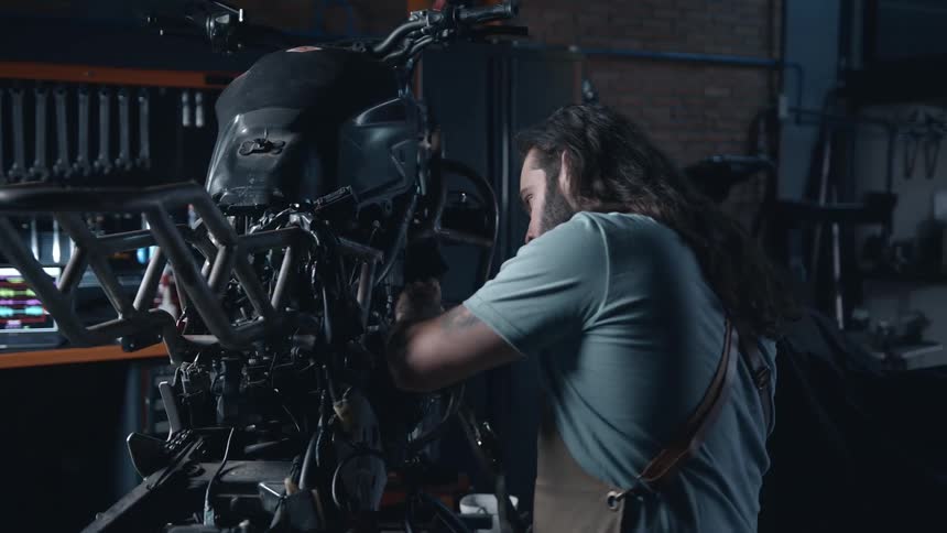 A man works on a motorcycle inside a mechanic workshop
