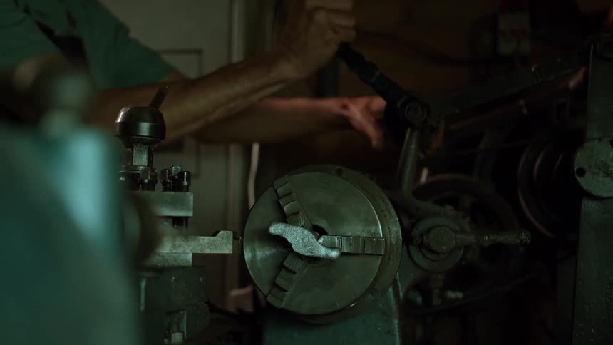A skilled workers hands expertly manipulate the controls of a heavyduty industrial lathe actively engaged in a metalworking process