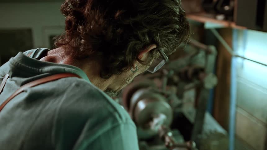 A man works in a workshop using a filing tool