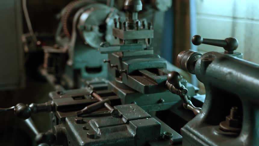 A closeup shows a metal lathe machine ready for precision machining work