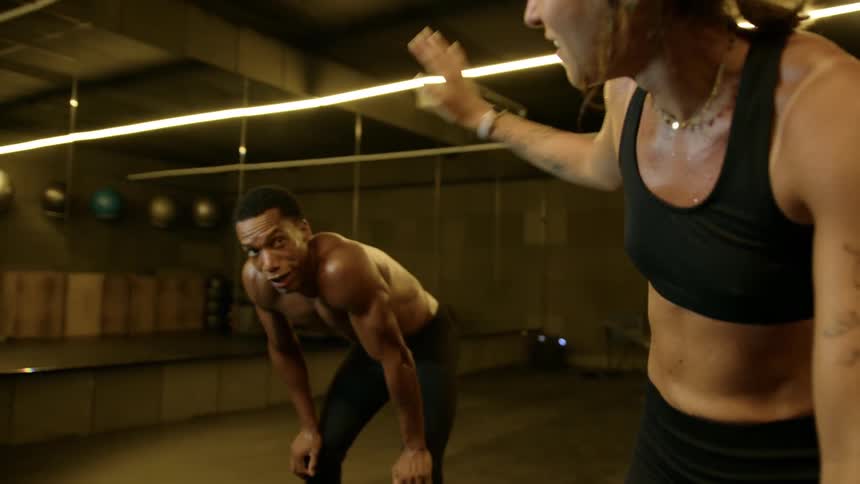 Two exhausted athletes bend over catching their breath then shake hands