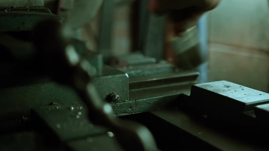 Person uses a brush to remove metal shavings from a surface on a workshop bench