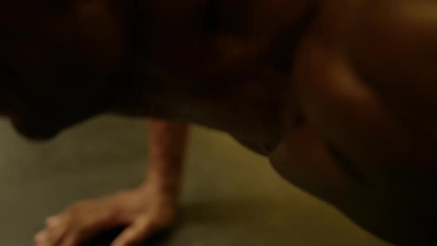 Shirtless man sweats while doing push ups