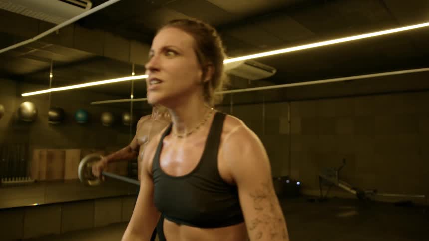 Woman and a man in a gym with determined expression doing biceps training with weight