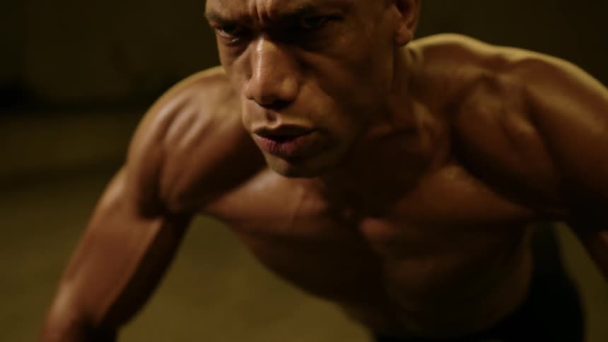 Fit strong male doing push ups indoors on concrete floor