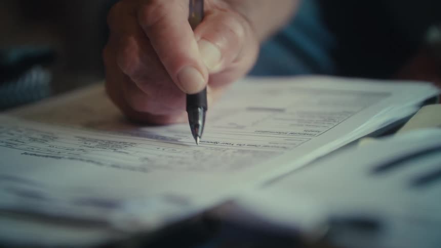 The man is filling out a form with a pen