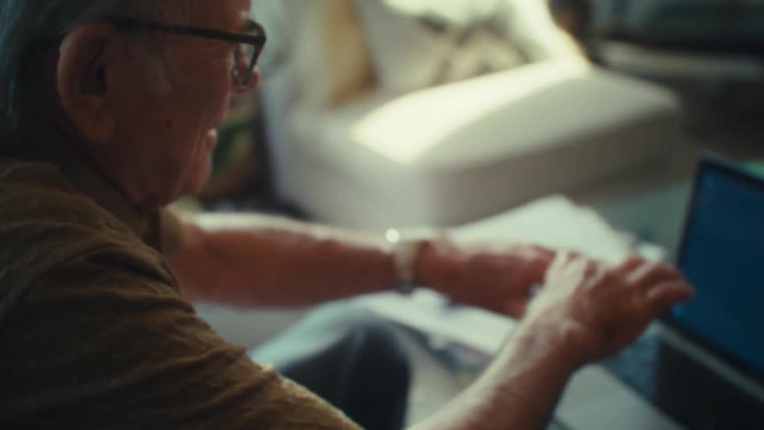 Vibrant and happy senior man typing on a laptop