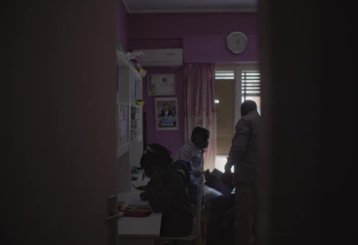 A domestic scene where individuals are engaged in various activities within a purplewalled room suggesting a study session in family