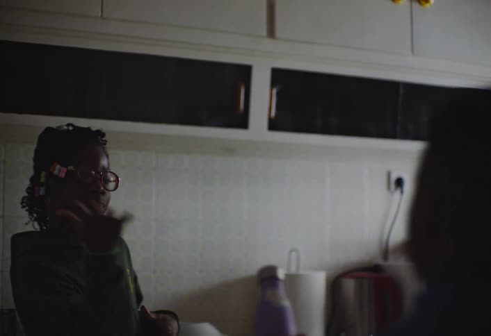 A mother prepares food using the microwave for her two kids as she pours liquid from one container into another