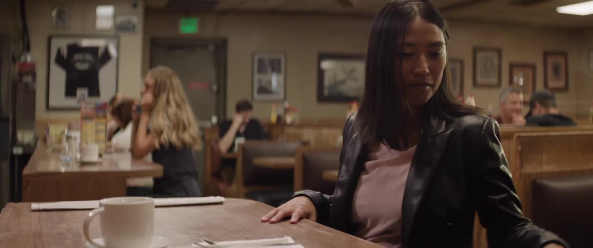 Woman sitting in a coffee shop and a person serving her