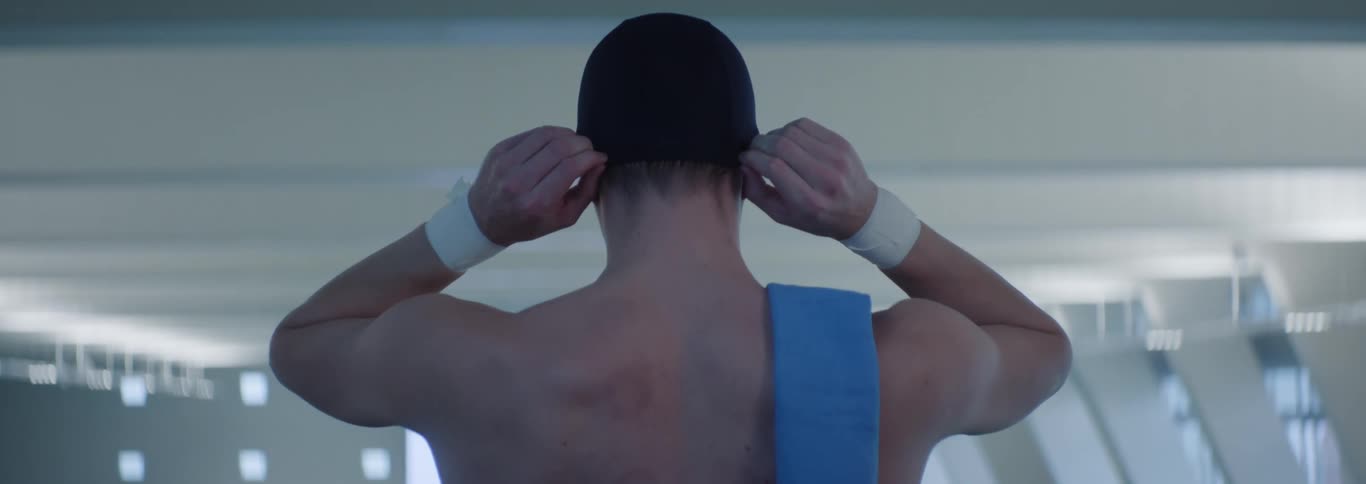 Man from behind adjusting a black swimming cap