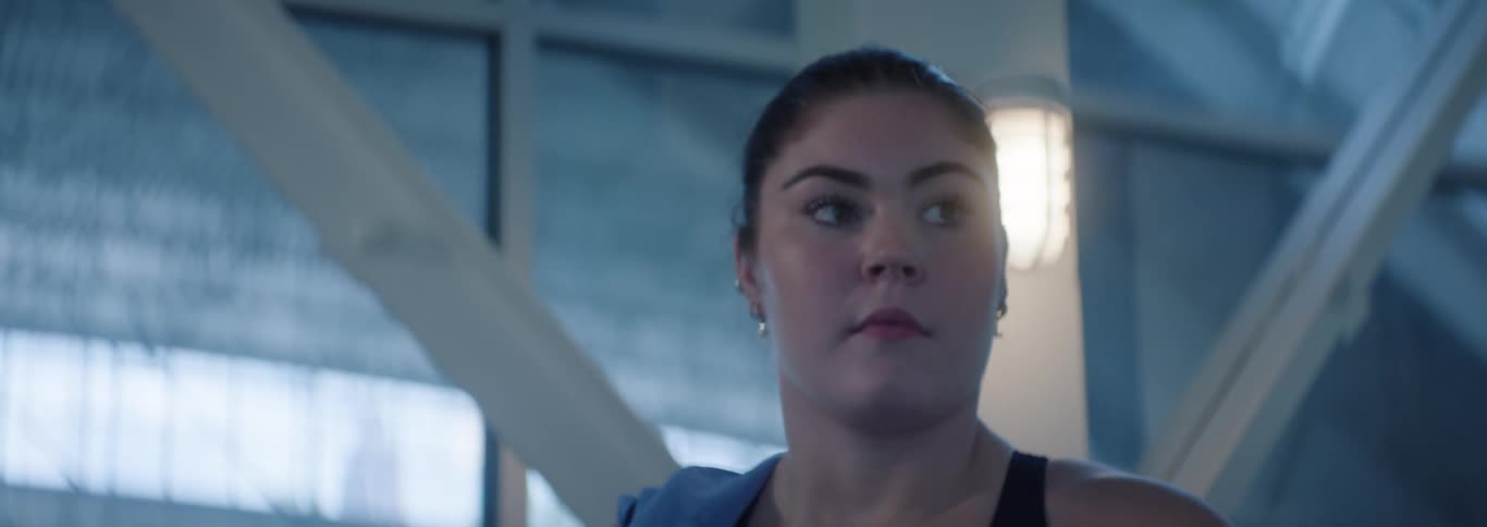 Woman with her hair tied up walking in an indoor space